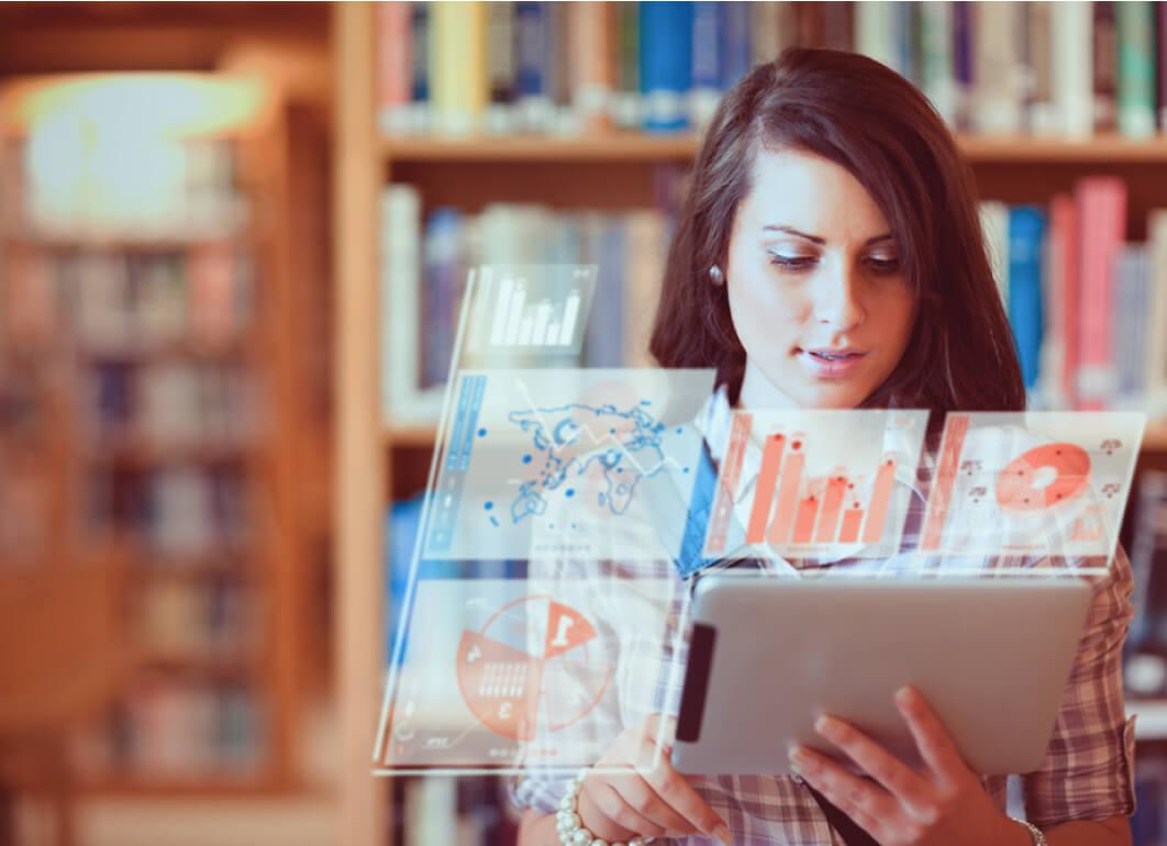 Person reviewing data on a tablet in front of bookshelves
